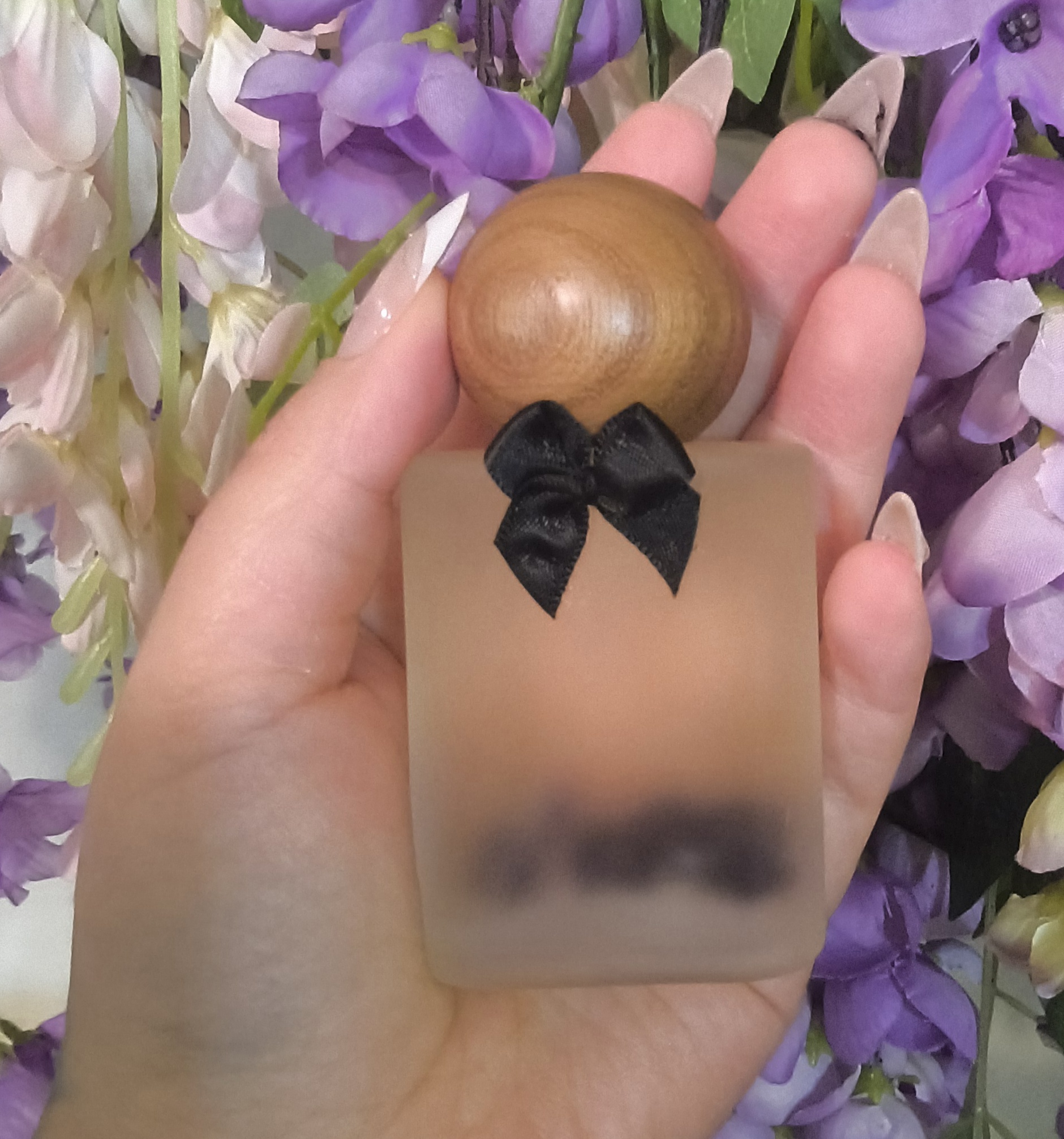 Intermediary- the frosted bottle with its wooden cap and black bow, held among wisteria